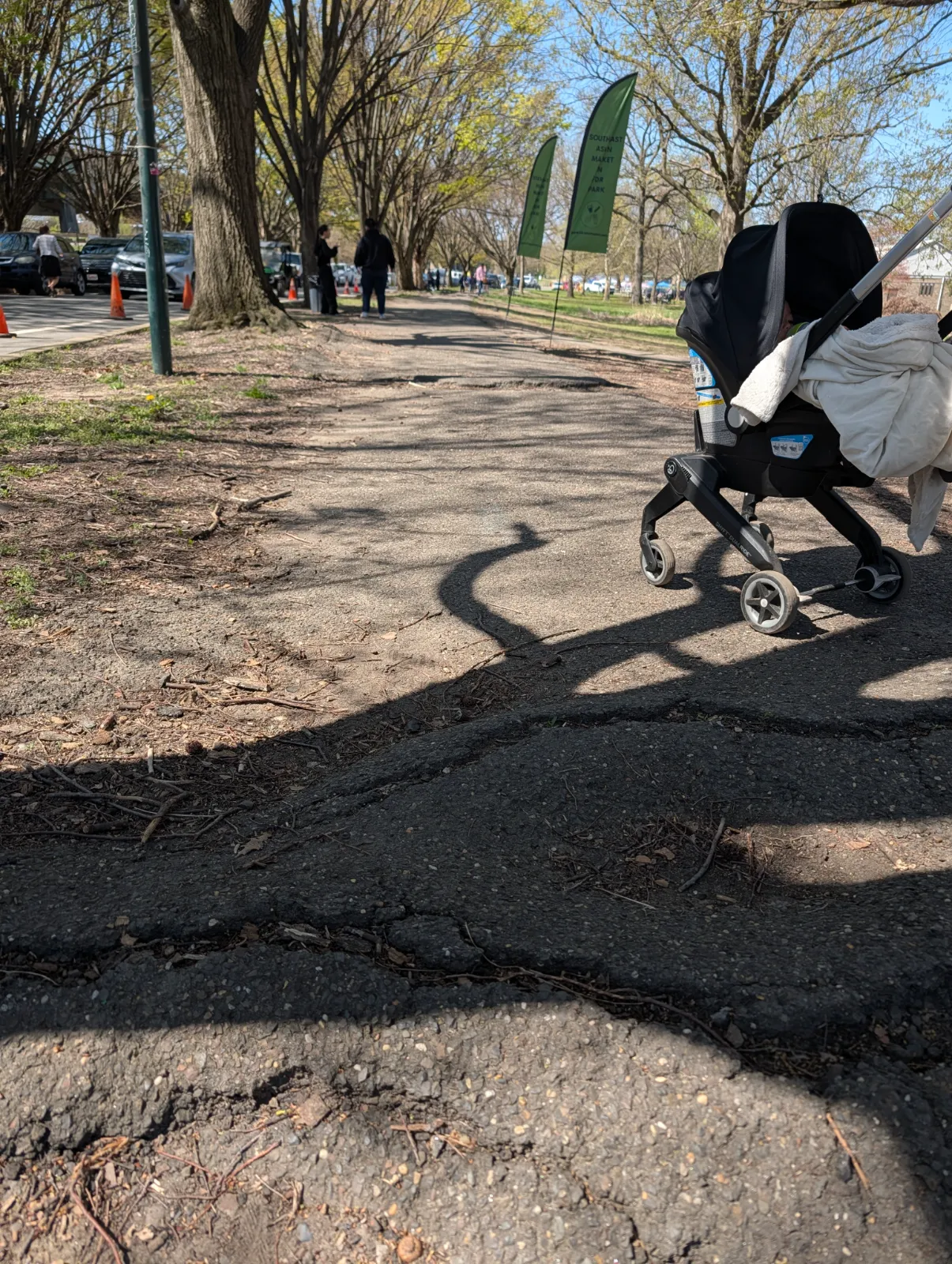 A stroller navigating bumpy, root-damaged pavement at FDR Park