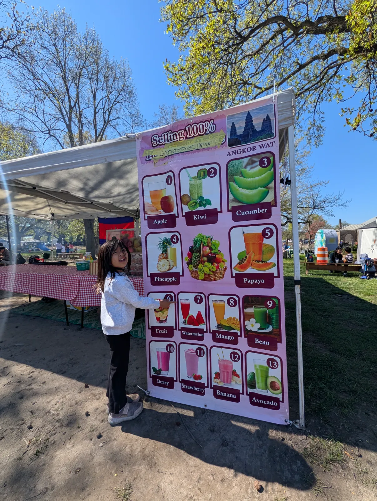 Charlotte standing in front of colorful smoothie menu signs at the Southeast Asian Market at FDR Park