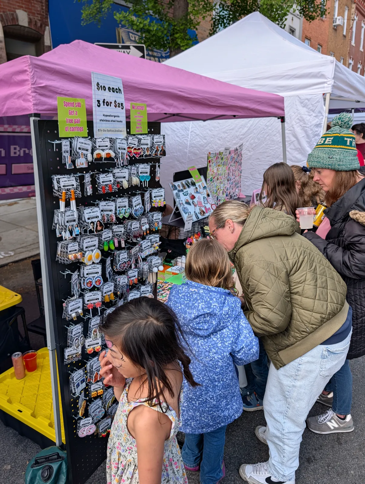 Families exploring a vendor tent with colorful accessories and handmade items