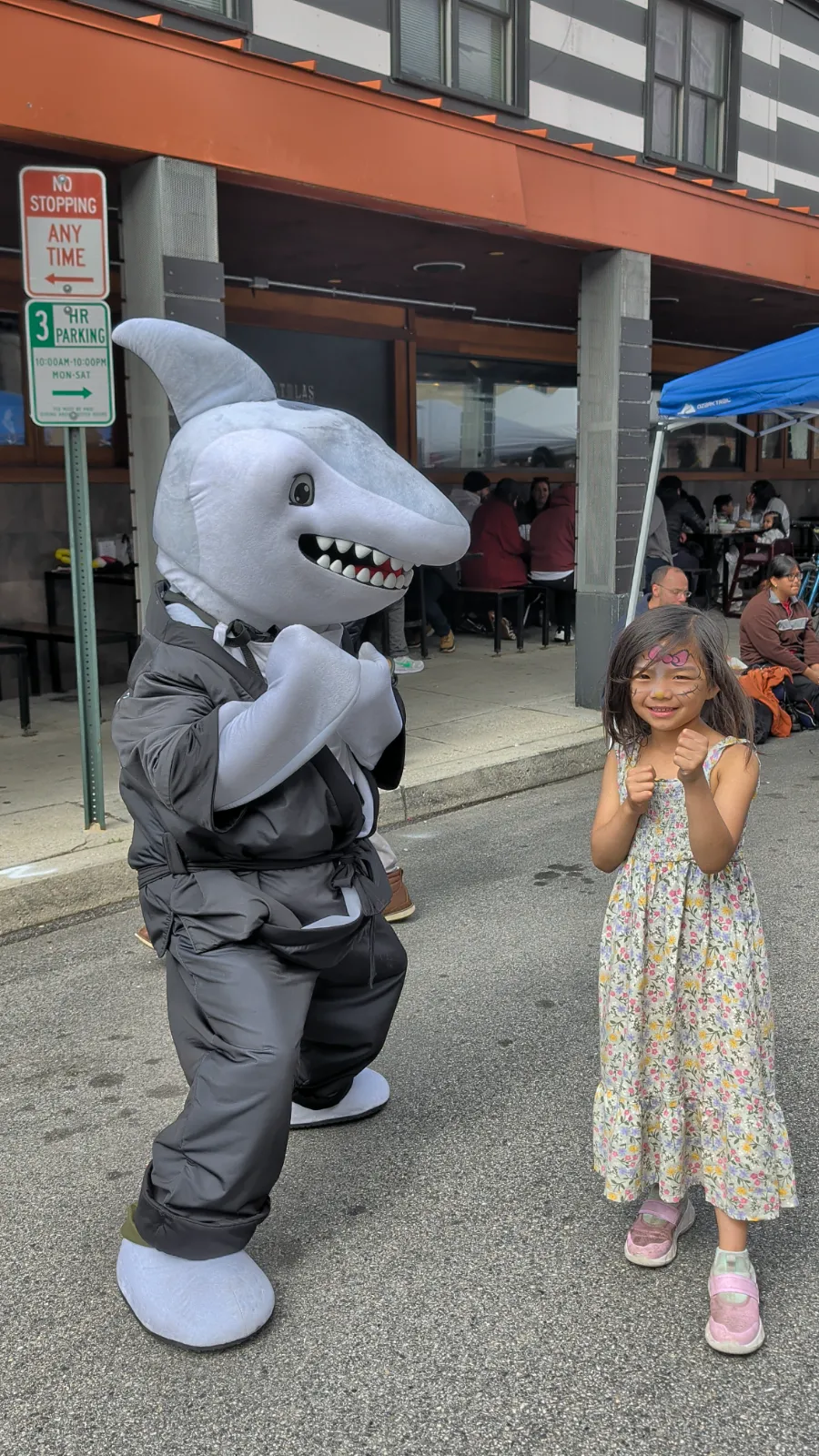 Charlotte giving a thumbs up while interacting with a shark mascot at Flavors on the Avenue