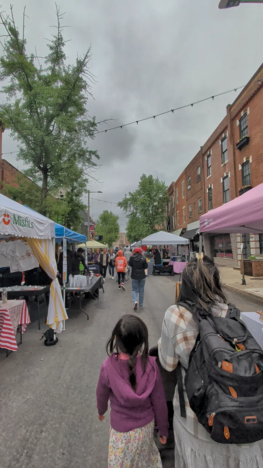 Families strolling through Flavors on the Avenue with colorful vendor tents lining East Passyunk