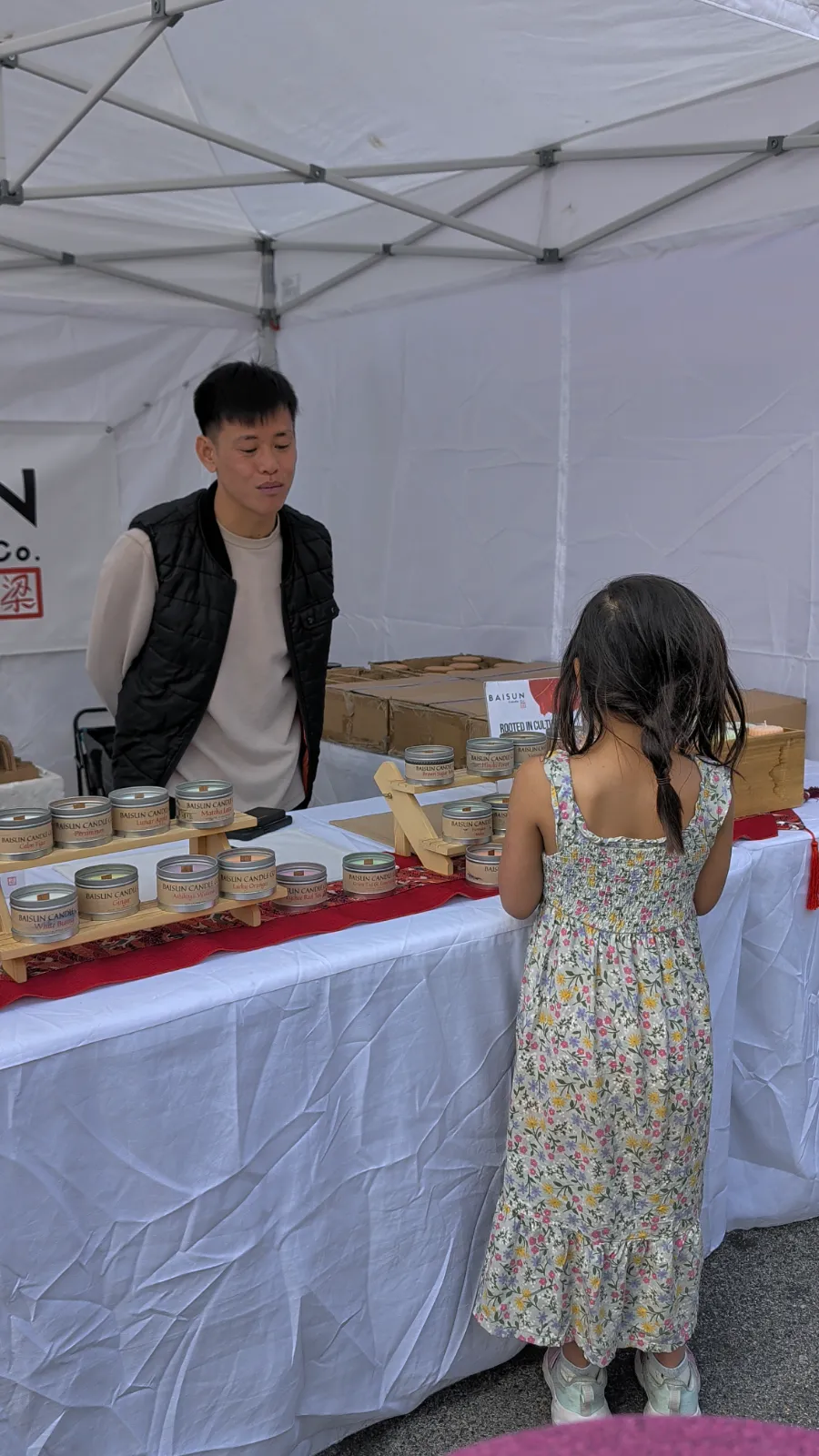 Charlotte examining scented candles at a vendor stand at Flavors on the Avenue