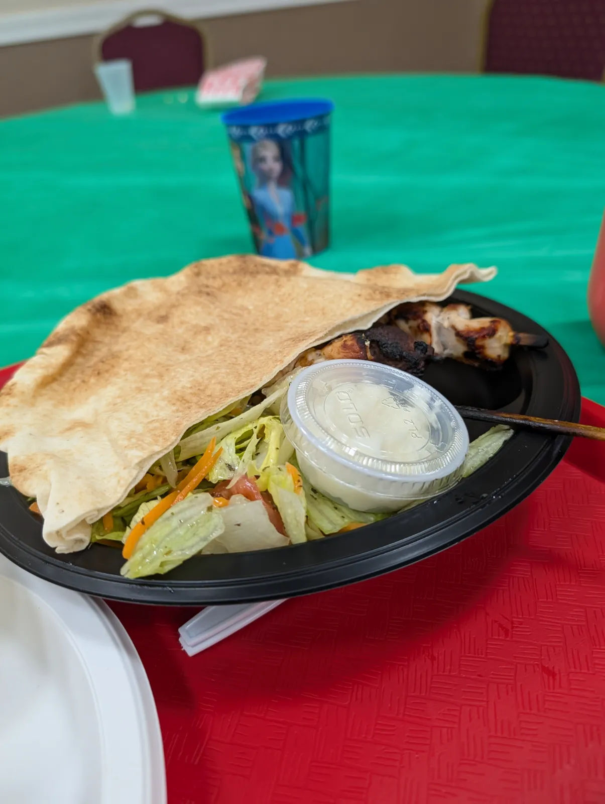 Seasoned grilled skewers with fresh salad and sauce served on a black tray at the Lebanese Festival