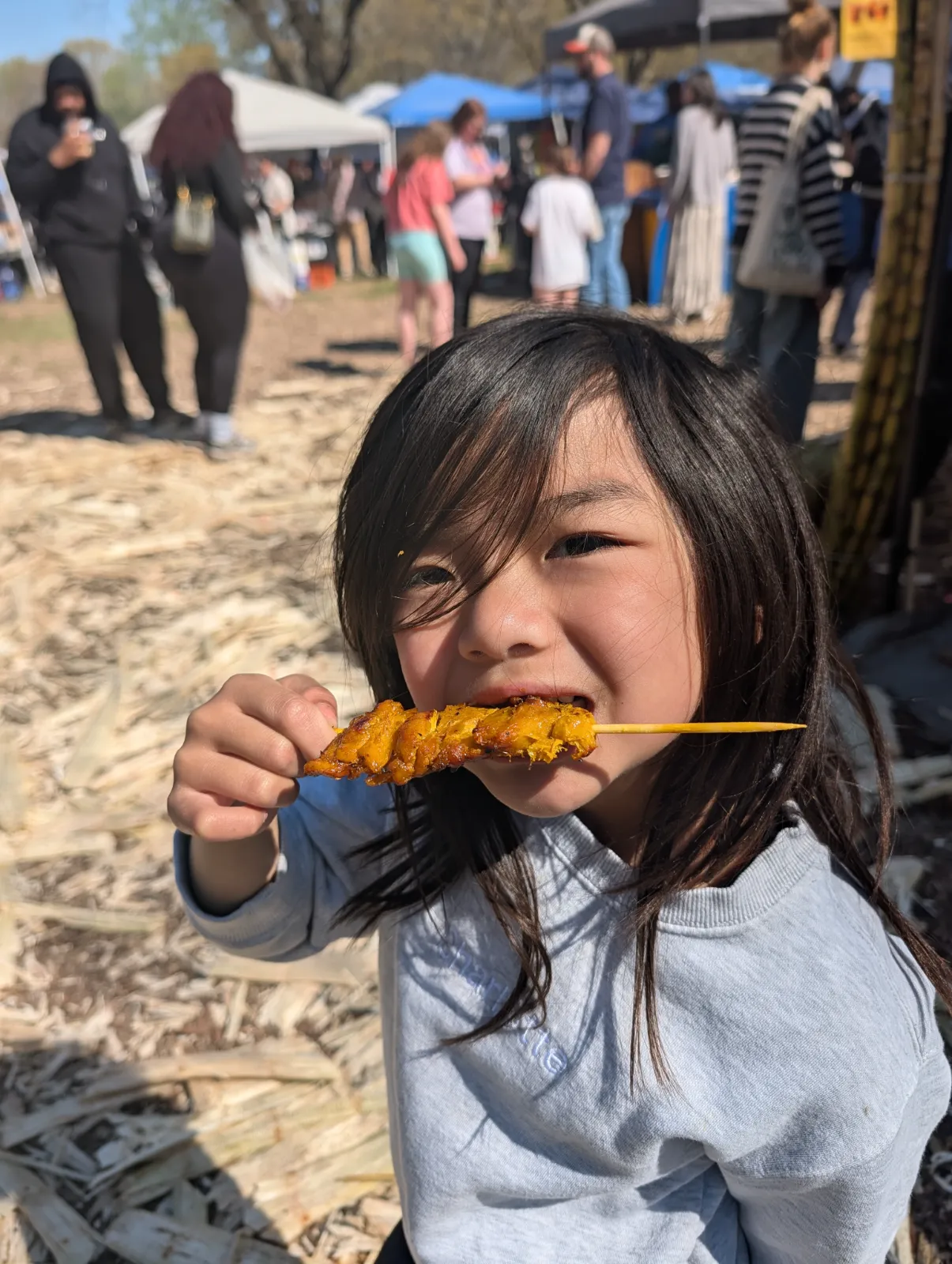 Charlotte biting into a chicken skewer