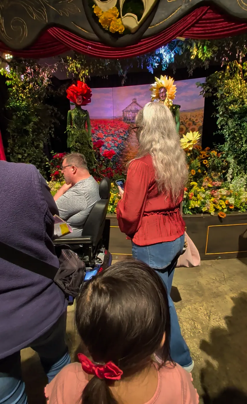 Charlotte trying to see the flower performers past adults towering above her at the Philly Flower Show