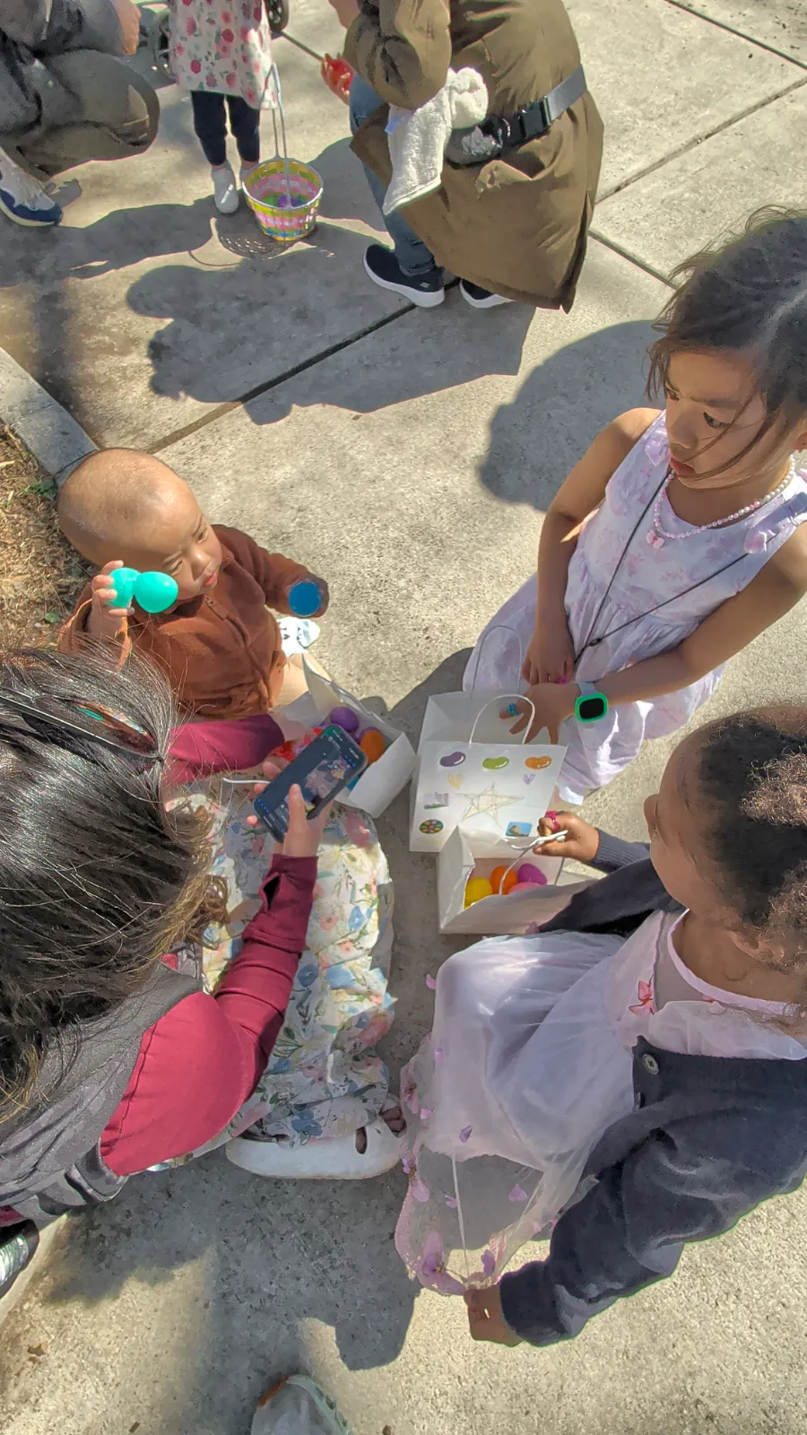 Children playing with colorful eggs at a community Easter event on a sunny day